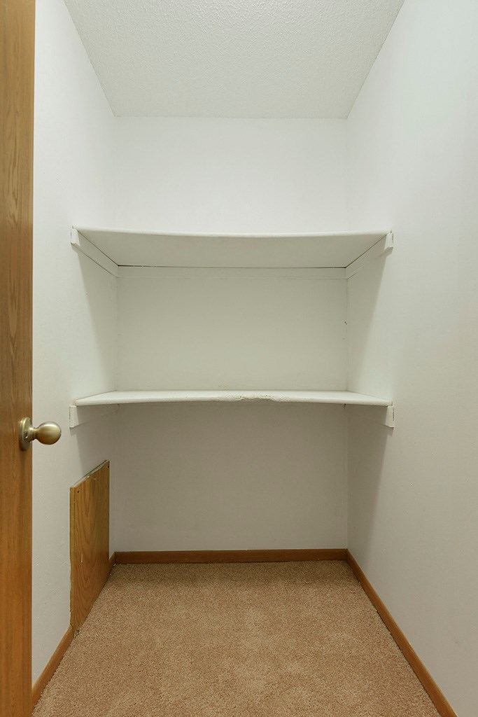 a small room with a white shelf on the wall and a door
