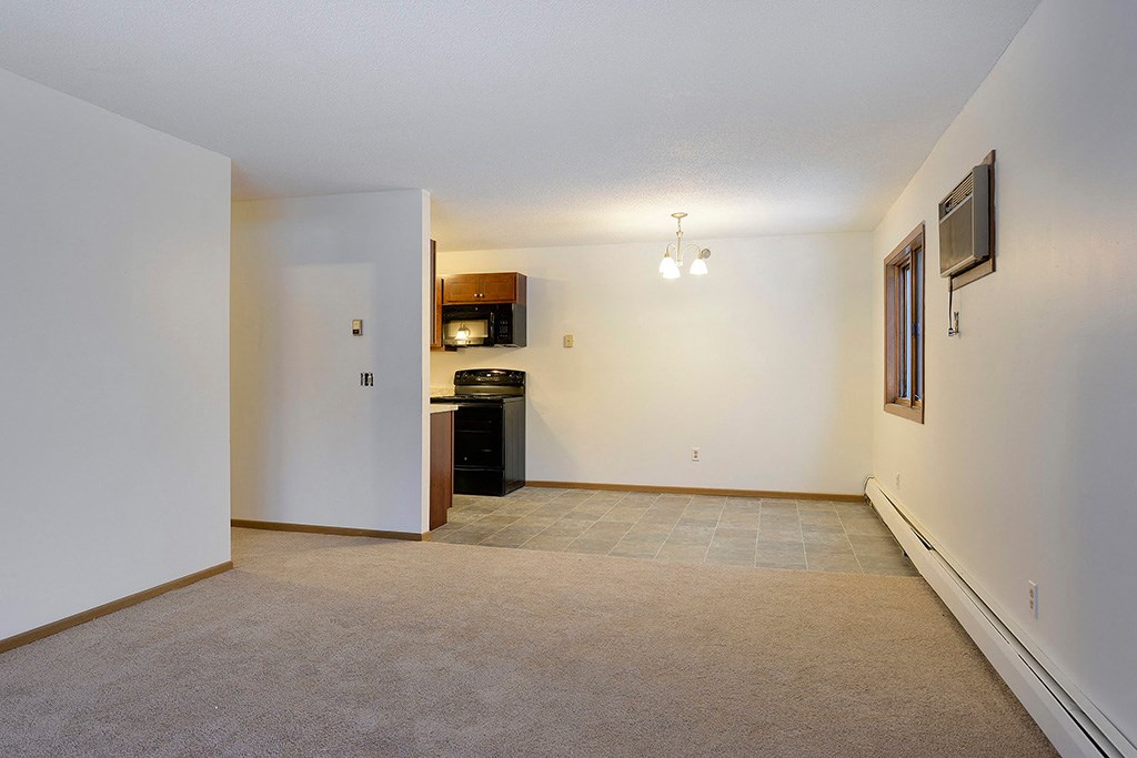 an empty living room and kitchen with white walls and carpet