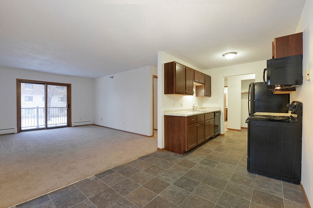 an empty kitchen and living room with a door to a balcony