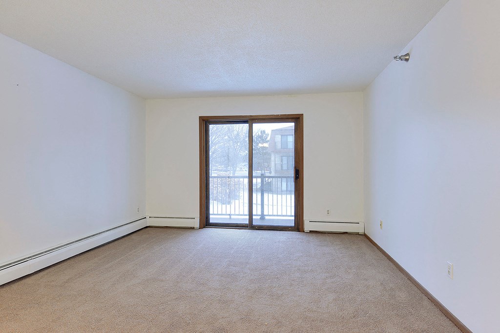 an empty living room with a door to a balcony