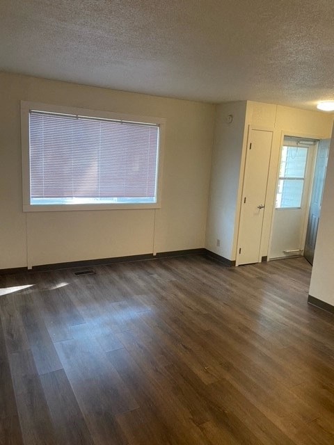 an empty living room with wood floors and a window