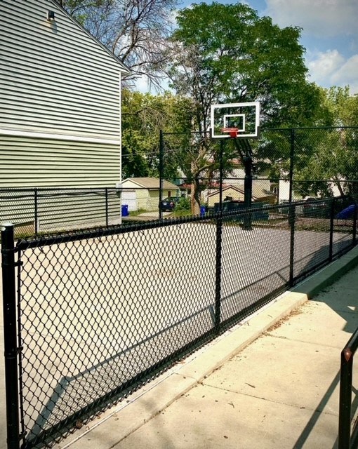 a court with a basketball hoop on a chain link fence