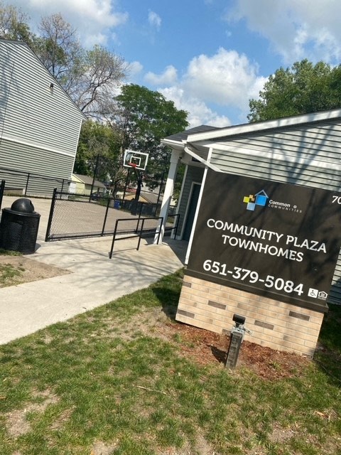 a sign for the community plaza townhomes in front of a basketball court