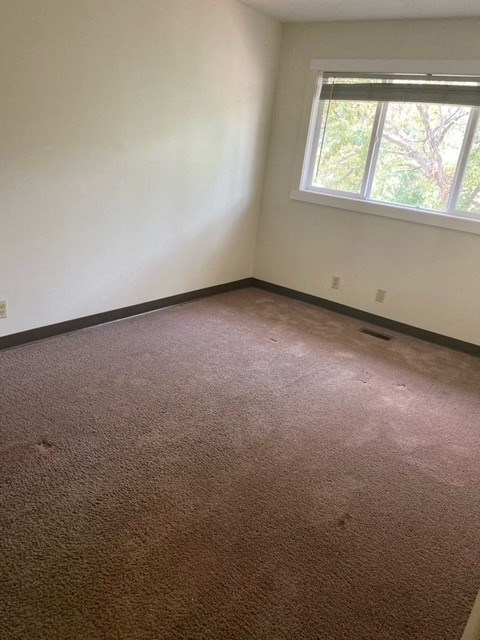 an empty room with a carpeted floor and a window