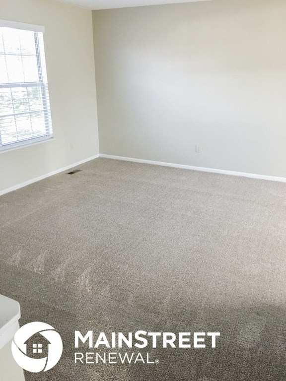 a carpeted room with white walls and a window