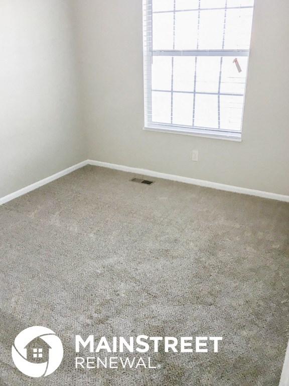 a carpeted room with a window and a concrete floor