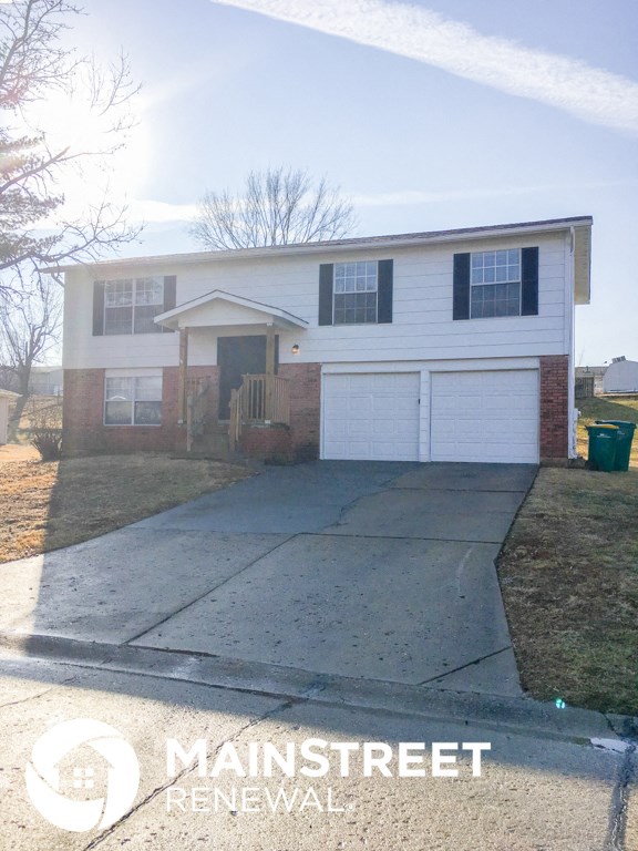 a home with a driveway and a white house