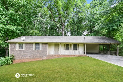 a small brick house with a lawn and trees