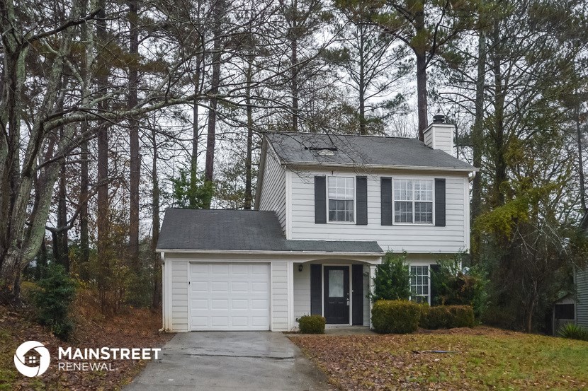 a white house with a gray roof in the woods