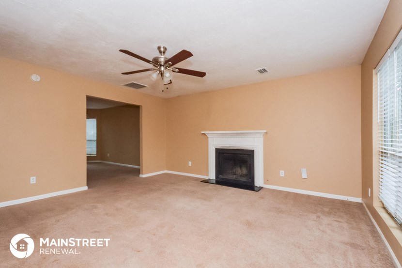 the living room with fireplace and ceiling fan