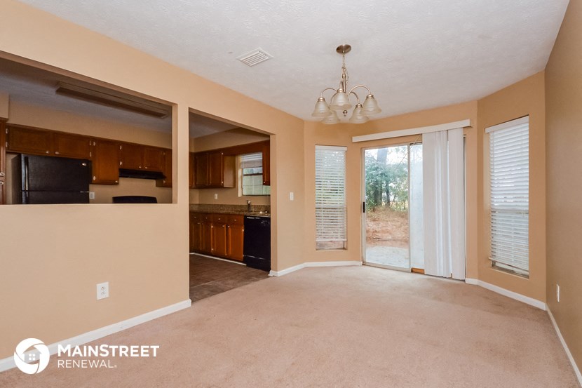 an empty living room with a kitchen and a chandelier