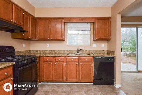 a kitchen with wooden cabinets and a black dishwasher and a sink