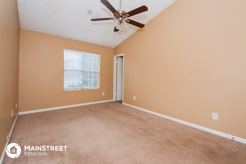 the master bedroom has a carpeted floor and a ceiling fan
