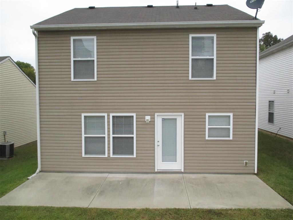 the front of a tan house with a porch and a white door