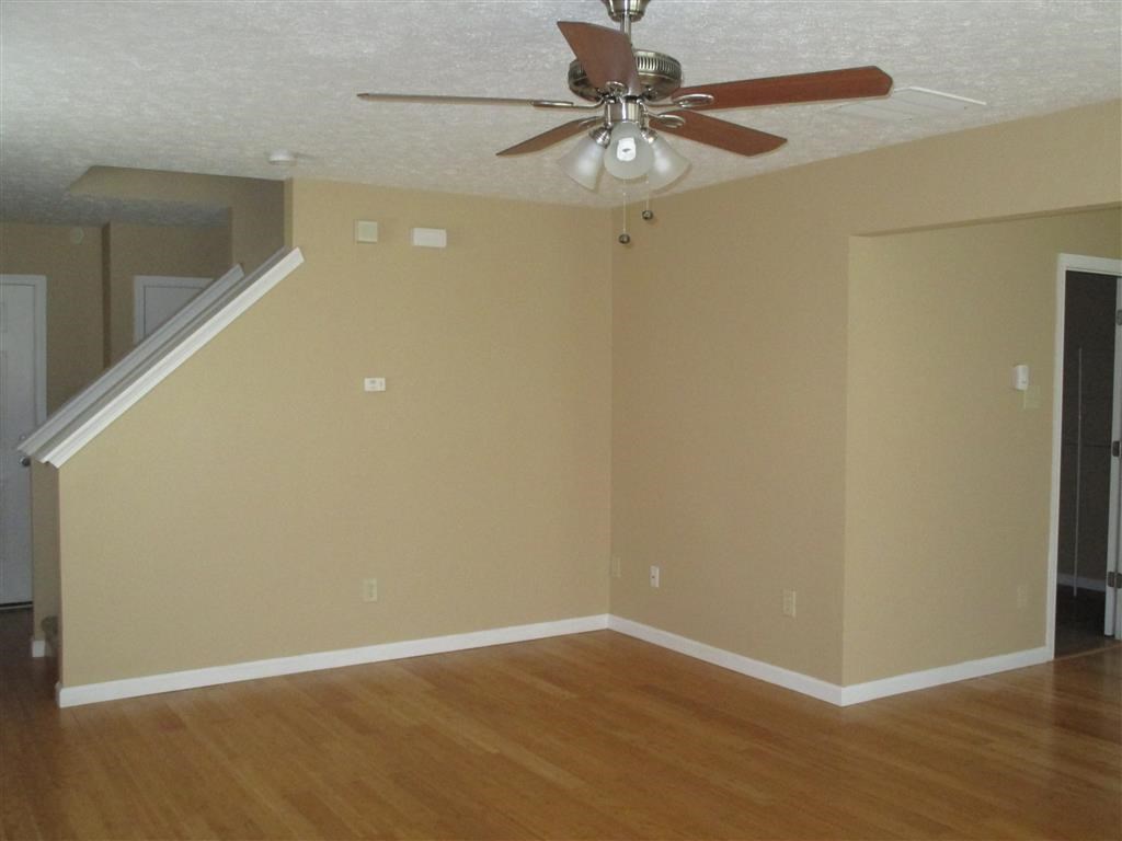 an empty living room with a ceiling fan