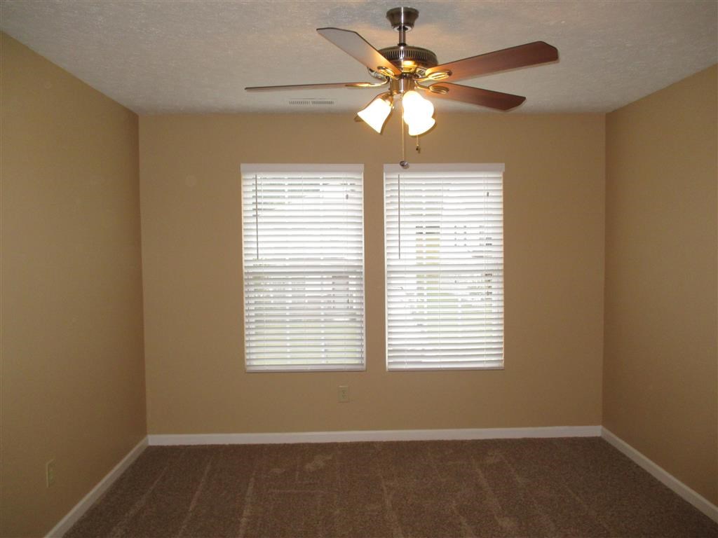 a living room with a ceiling fan and two windows