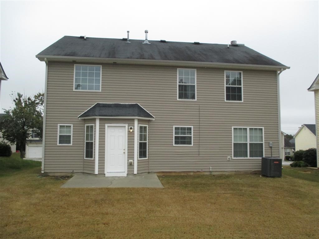the back of a house with a white door and a driveway