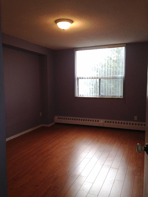 A room with a window and a wooden floor.
