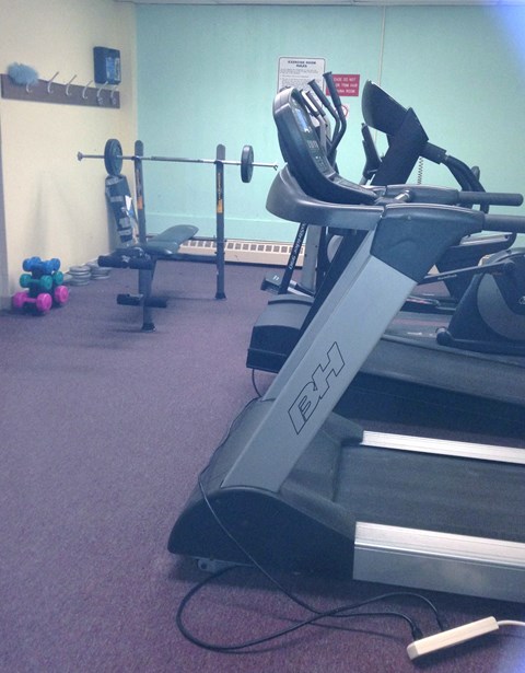 A treadmill with a sign on the wall behind it.