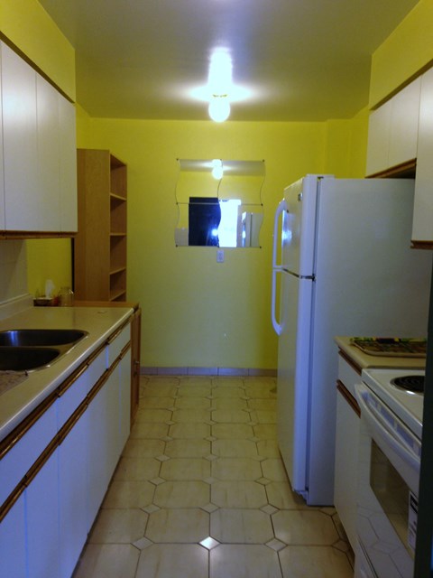 A kitchen with a white refrigerator and a black sink.