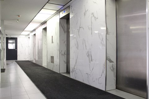 a hallway with marble walls and doors in a building