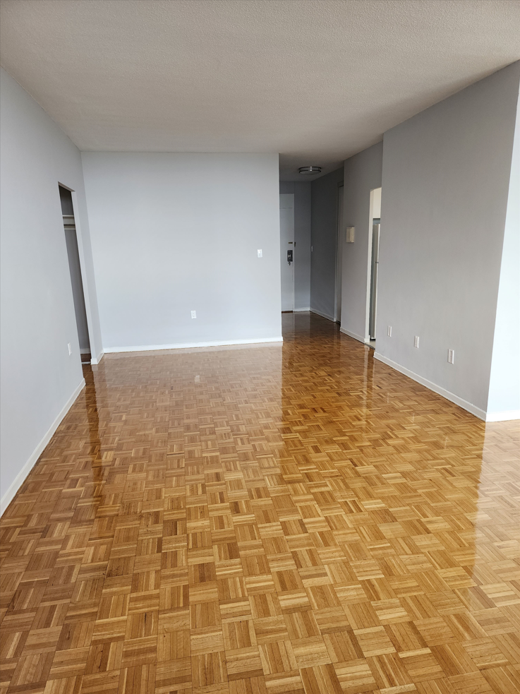 an empty living room with wood flooring and white walls