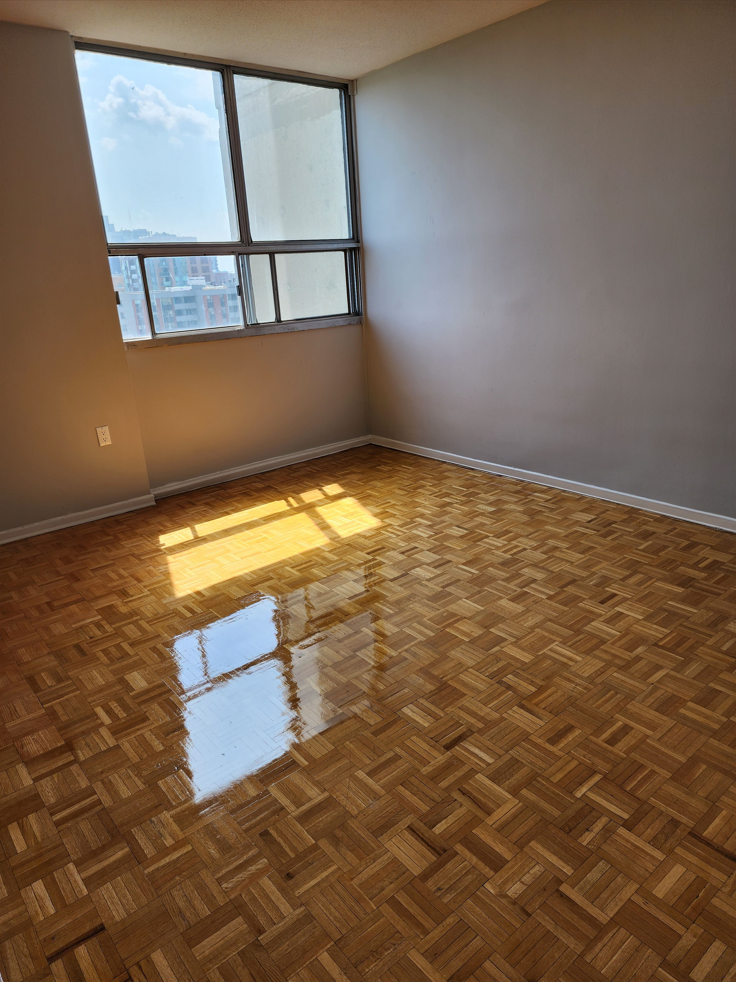 an empty living room with wood flooring and a window