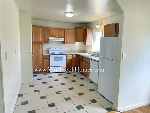 A kitchen with a white stove top oven and a white refrigerator.