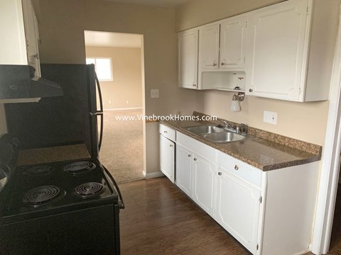 A kitchen with white cabinets and a black stove top oven.