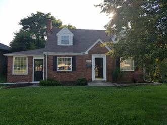 a front view of a brick house with a green lawn
