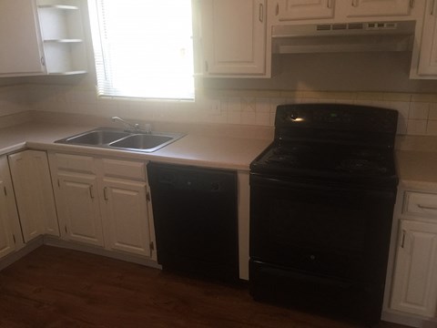 A black dishwasher is in a kitchen with white cabinets.