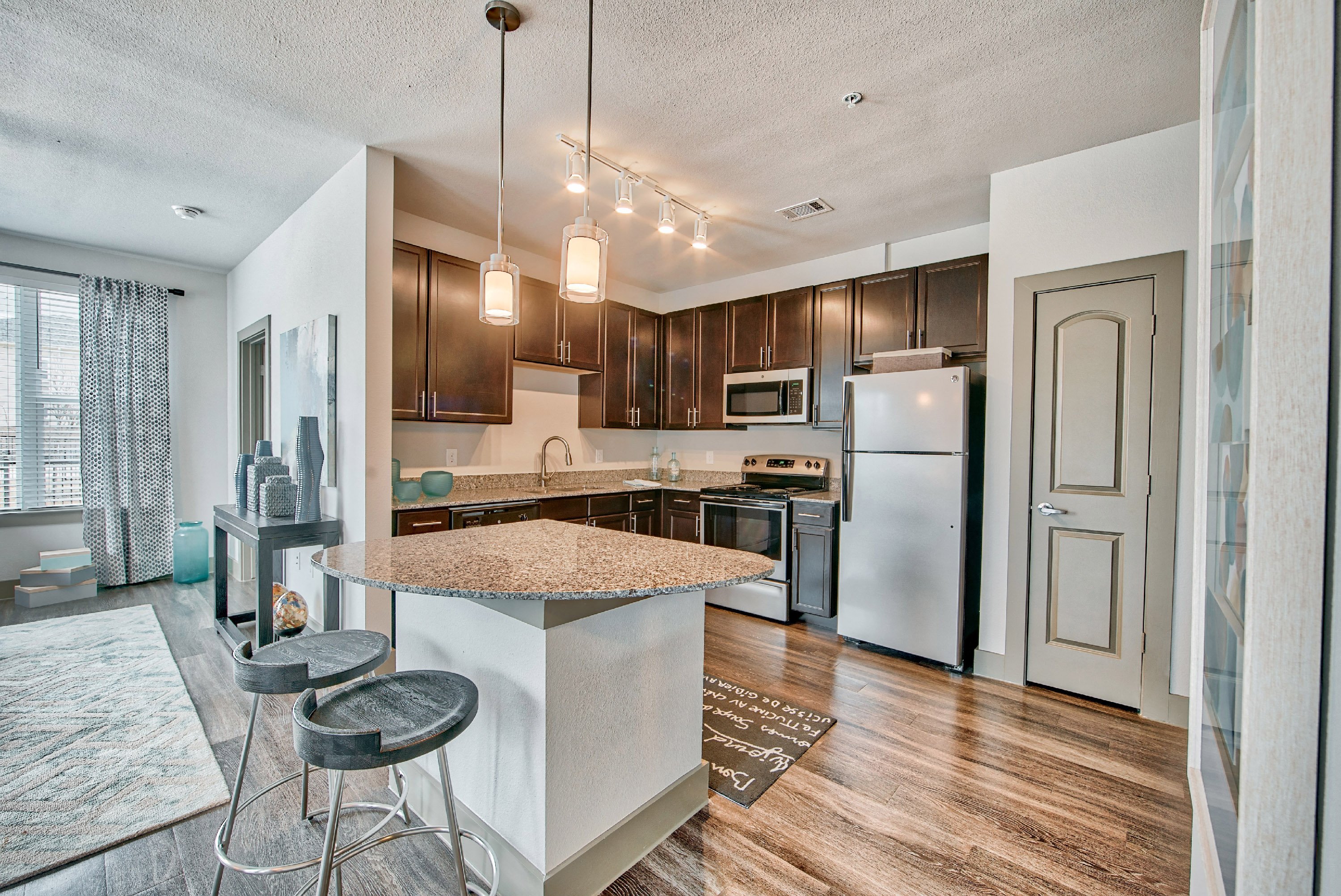 a kitchen with an island with stools and a refrigerator