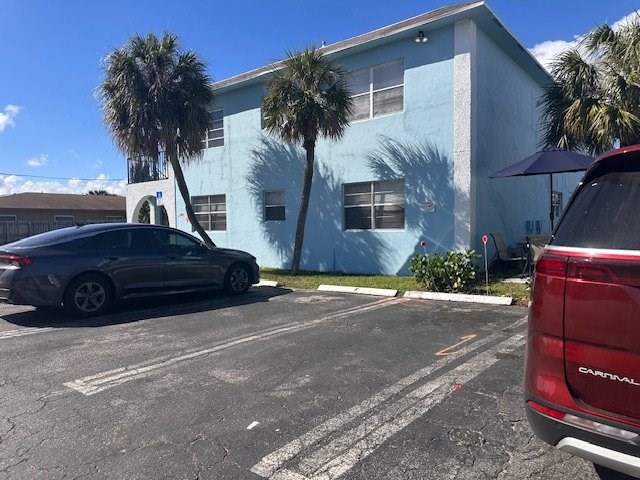A car is parked in a parking lot in front of a blue building.