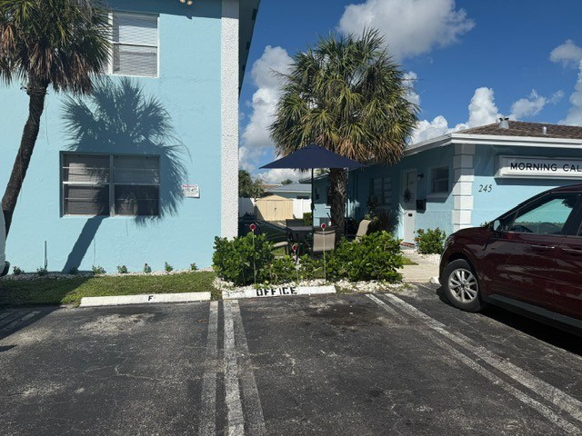 A red car is parked in a parking lot in front of a blue building.