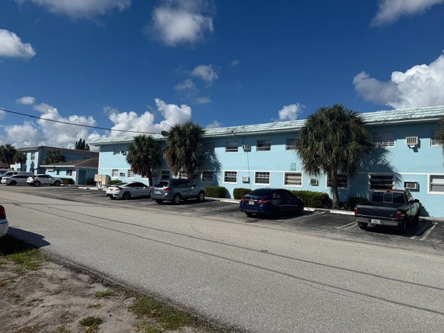 A street with cars parked and a blue building in the background.