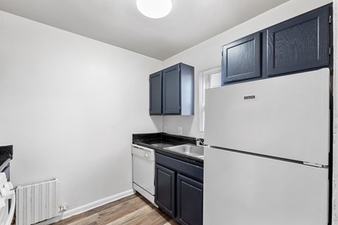 A white refrigerator stands in a kitchen with black cabinets.