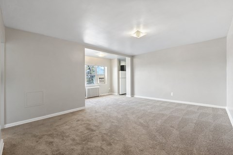 A spacious room with a carpeted floor and a window.