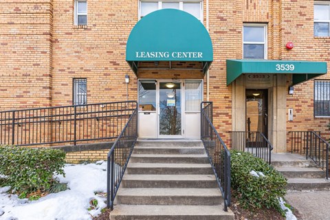A brick building with a green awning that says Leasing Center.