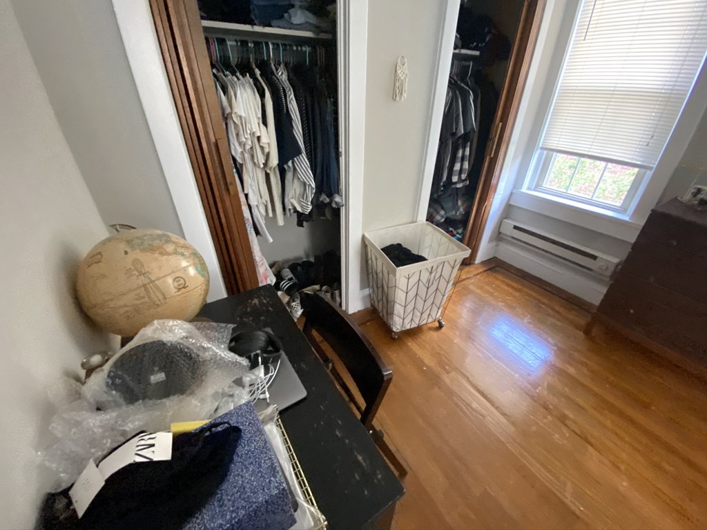 a room with a desk and a closet with clothes in it