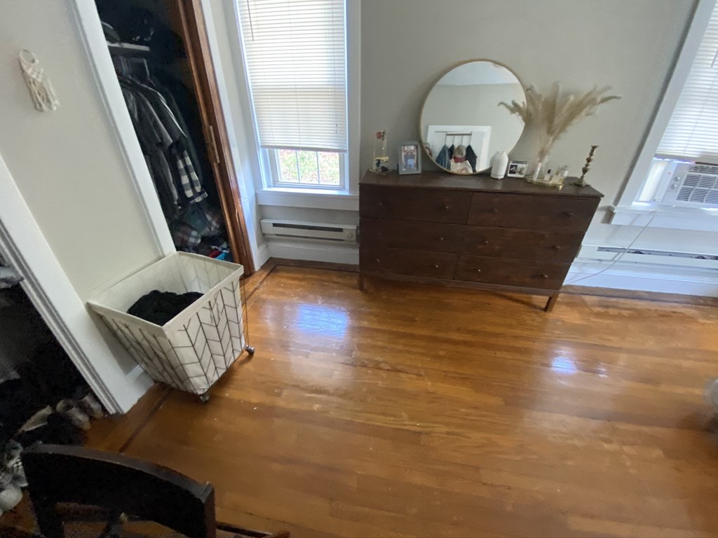 a living room with wooden floors and a mirror on a dresser