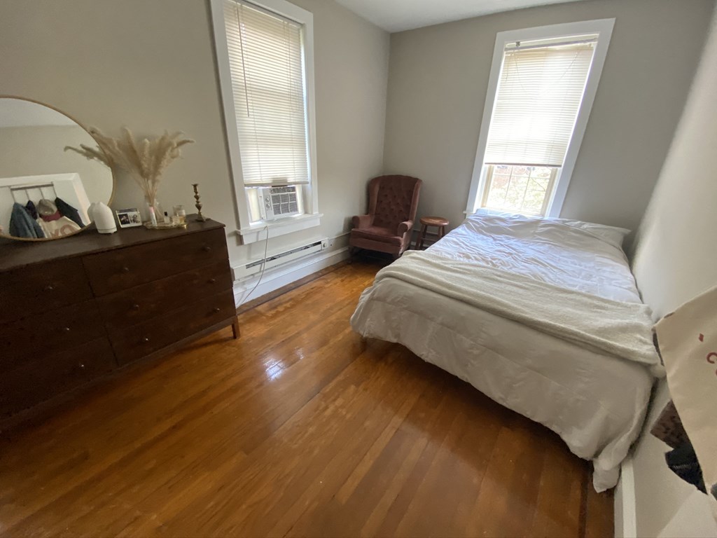 a bedroom with a bed and a dresser and two windows