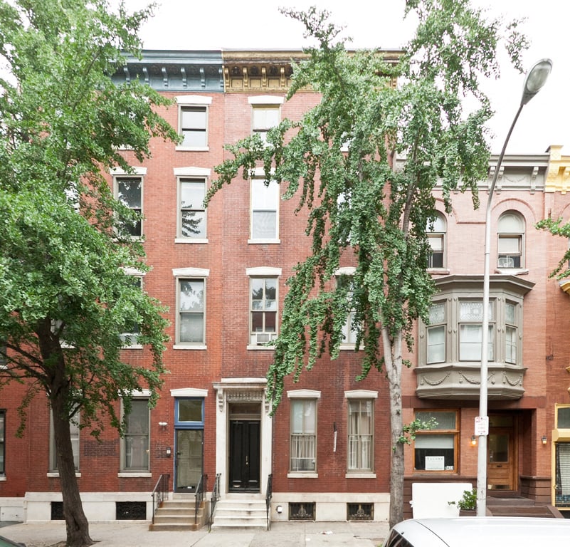 A red brick building with a tree in front of it.