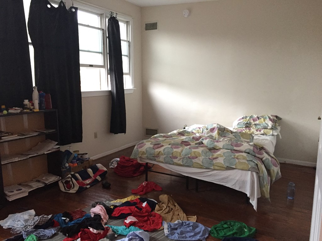 a bedroom with a bed and a pile of clothes on the floor