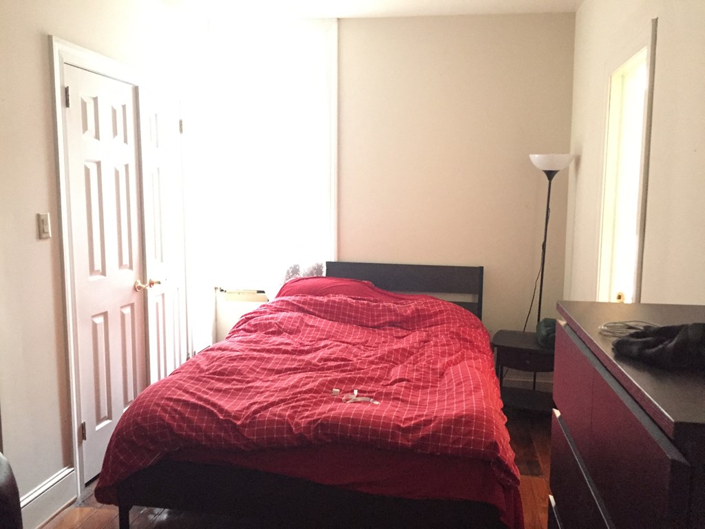 a bedroom with a bed and a dresser and a door