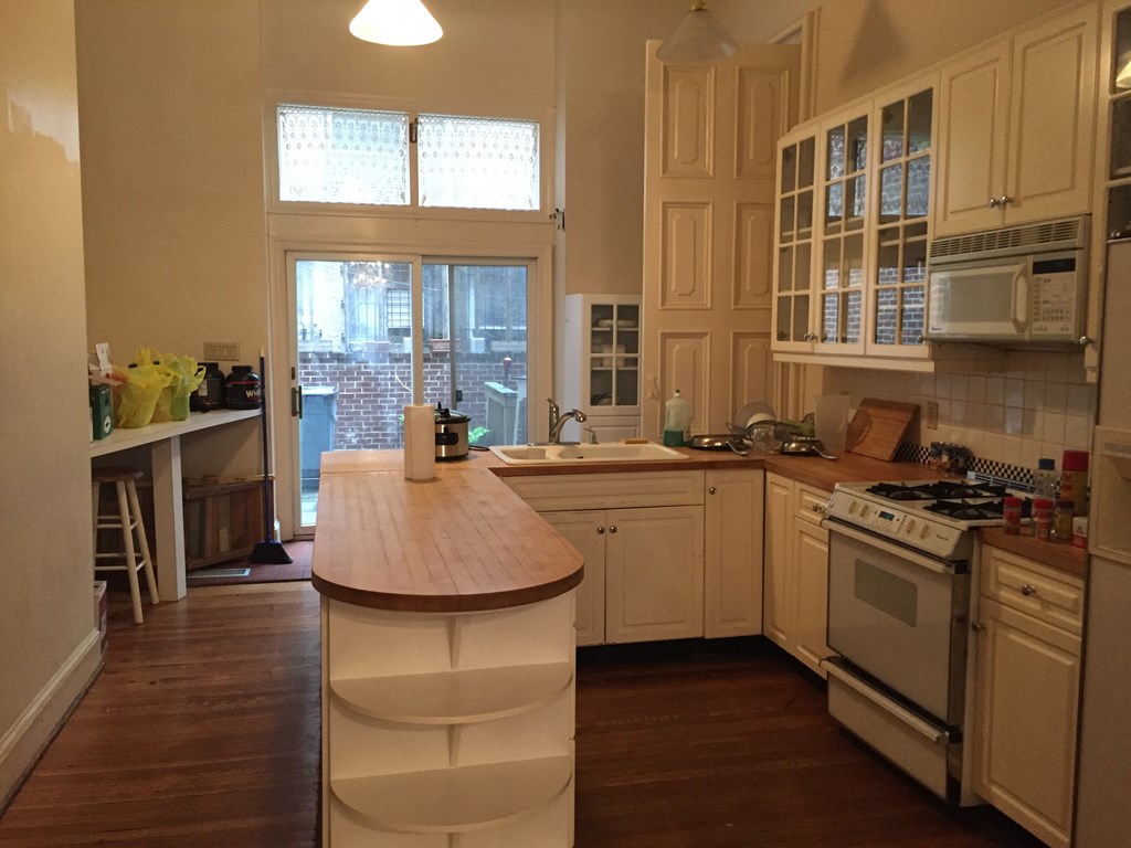 a kitchen with white cabinets and a wooden counter top