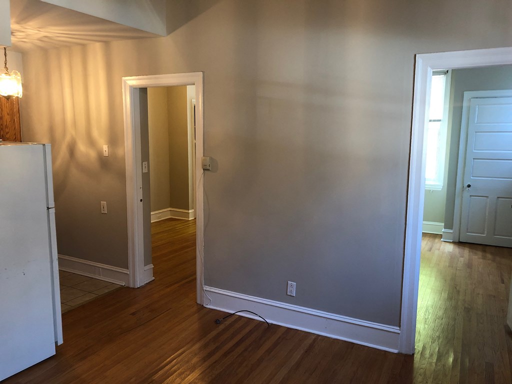an empty living room with a door open to a hallway