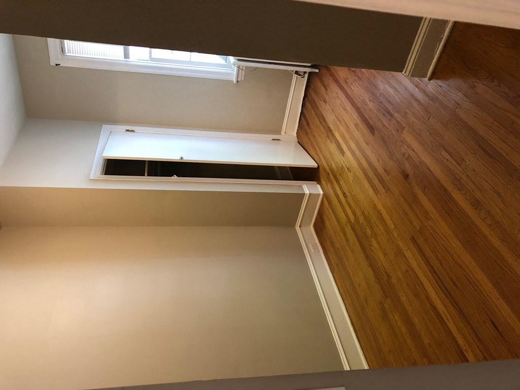 the bottom of a set of stairs with a window and wood flooring