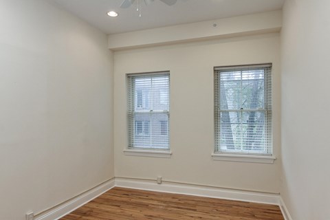 an empty room with two windows and a wooden floor