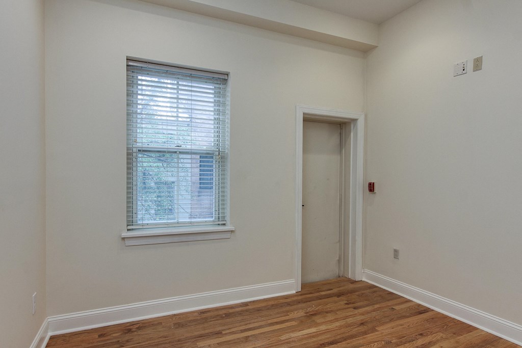 a bedroom with white walls and a window and a door