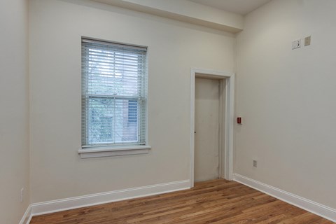 a bedroom with white walls and a window and a door